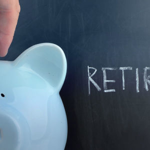 Coin being placed in piggy bank with retirement written on blackboard in background- representing simple super