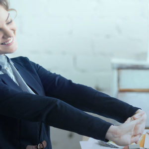 Happy employee stretching arms in front of computer