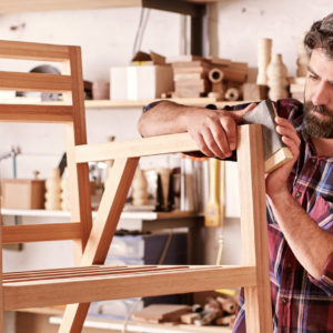 Furniture designer sanding a wooden chair frame