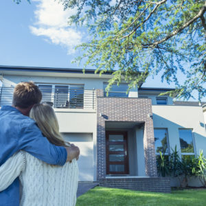 Couple standing in front of their new home