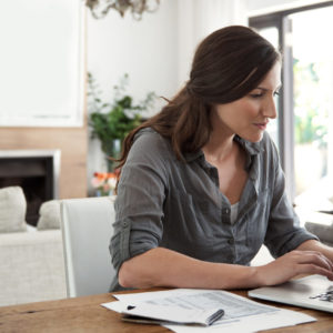 Shot of a woman using a laptop to track spending online