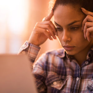 Frustrated woman reading something on laptop in the office representing entrepreneur burnout