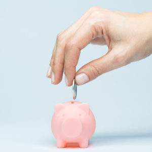 Hand putting a coin into piggy bank