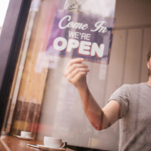 Man Turning Opening Sign on Door Coffee Shop - opening new business