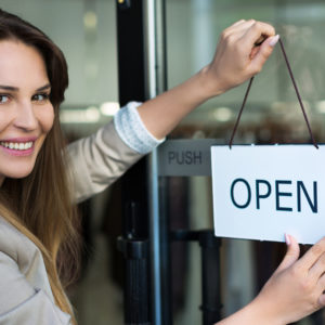 Woman opening her new business - open sign on door