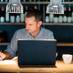 Business man doing the books at a restaurant - checking his employee's superannuation payments