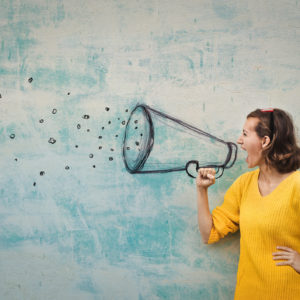 Young woman holding an imaginary megaphone and shouting into it, representing small business marketing communications