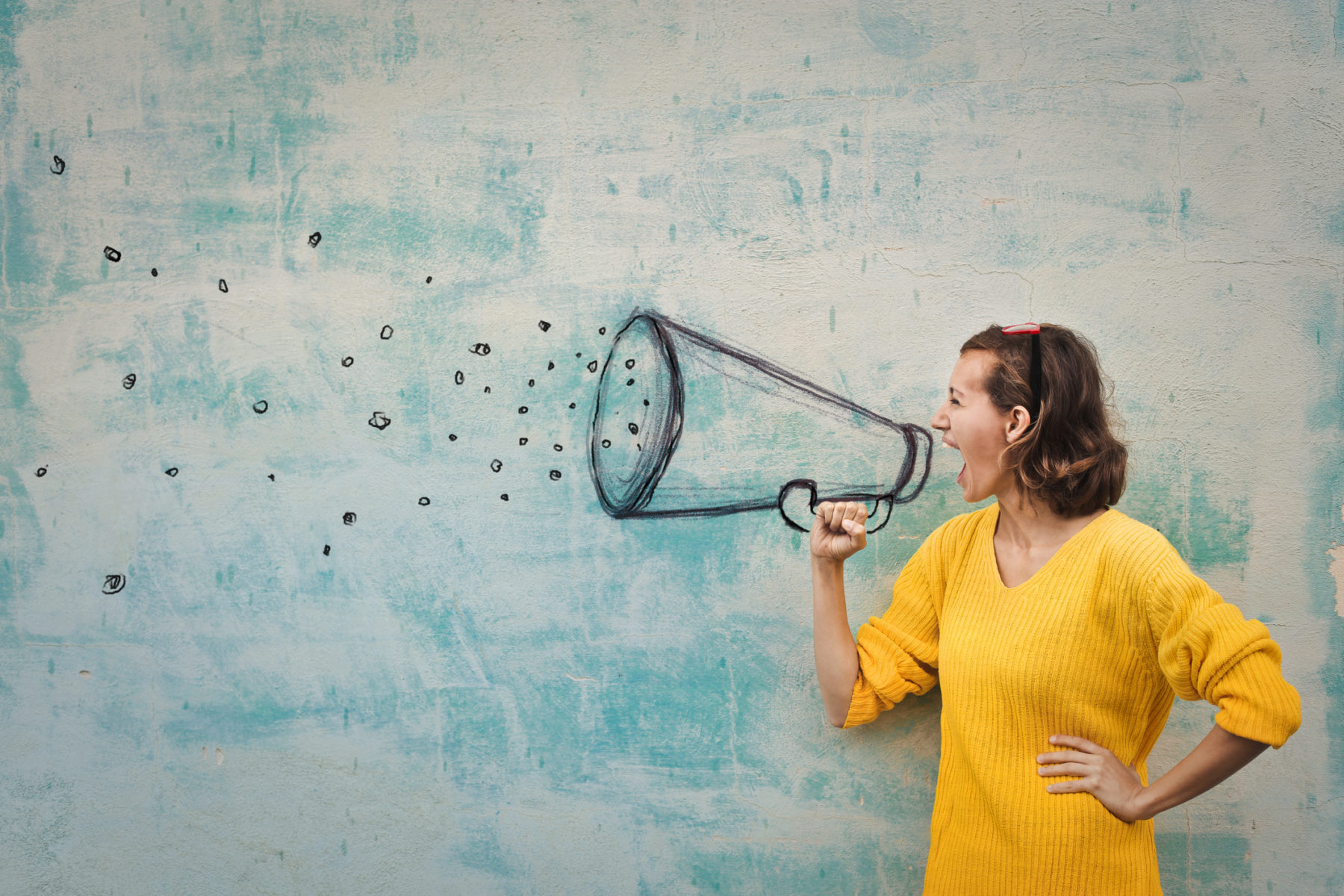 Young woman holding an imaginary megaphone and shouting into it, representing small business marketing communications