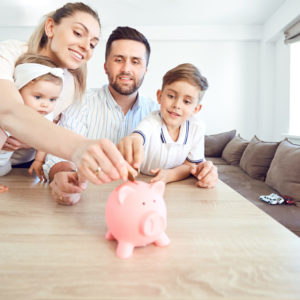 Death and TPD insurance concept - A family saves money with a piggy bank. Happy family at the table in the room.